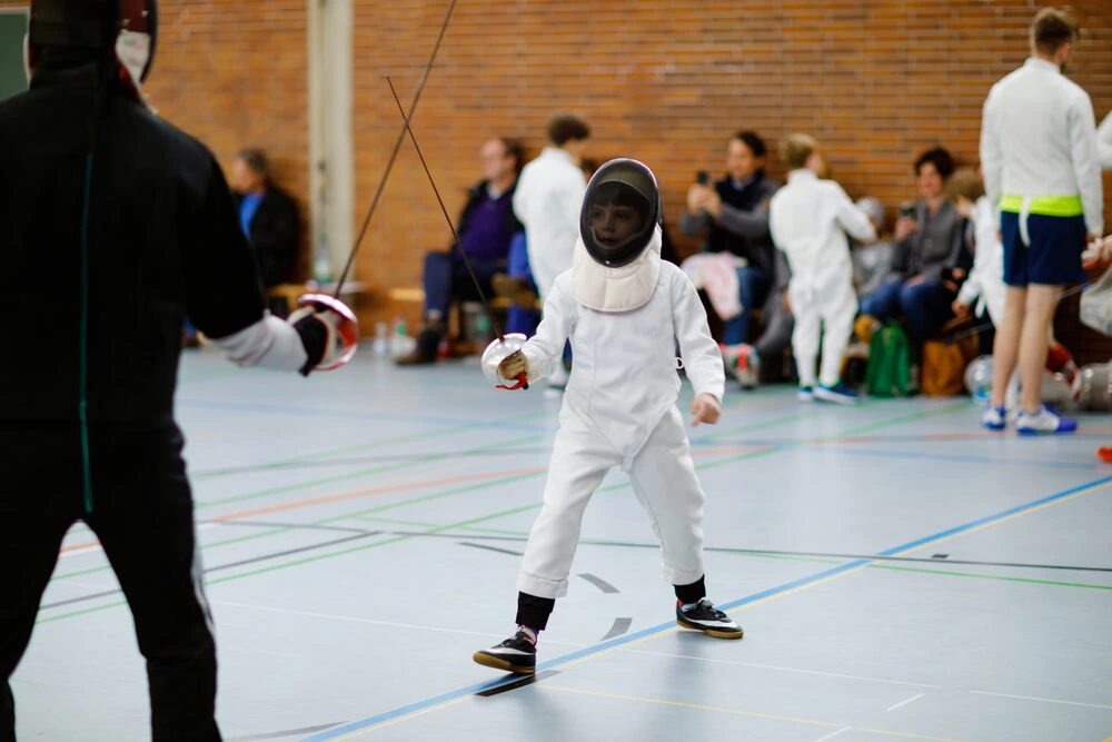 Little kid boy fencing on a fence competition.
