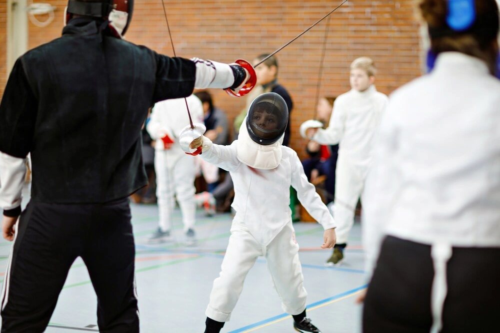 Little kid boy fencing on a fence competition.